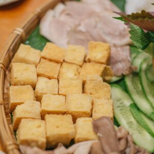 Delicious Vietnamese platter with tofu, cucumber, and herbs on a wooden table.