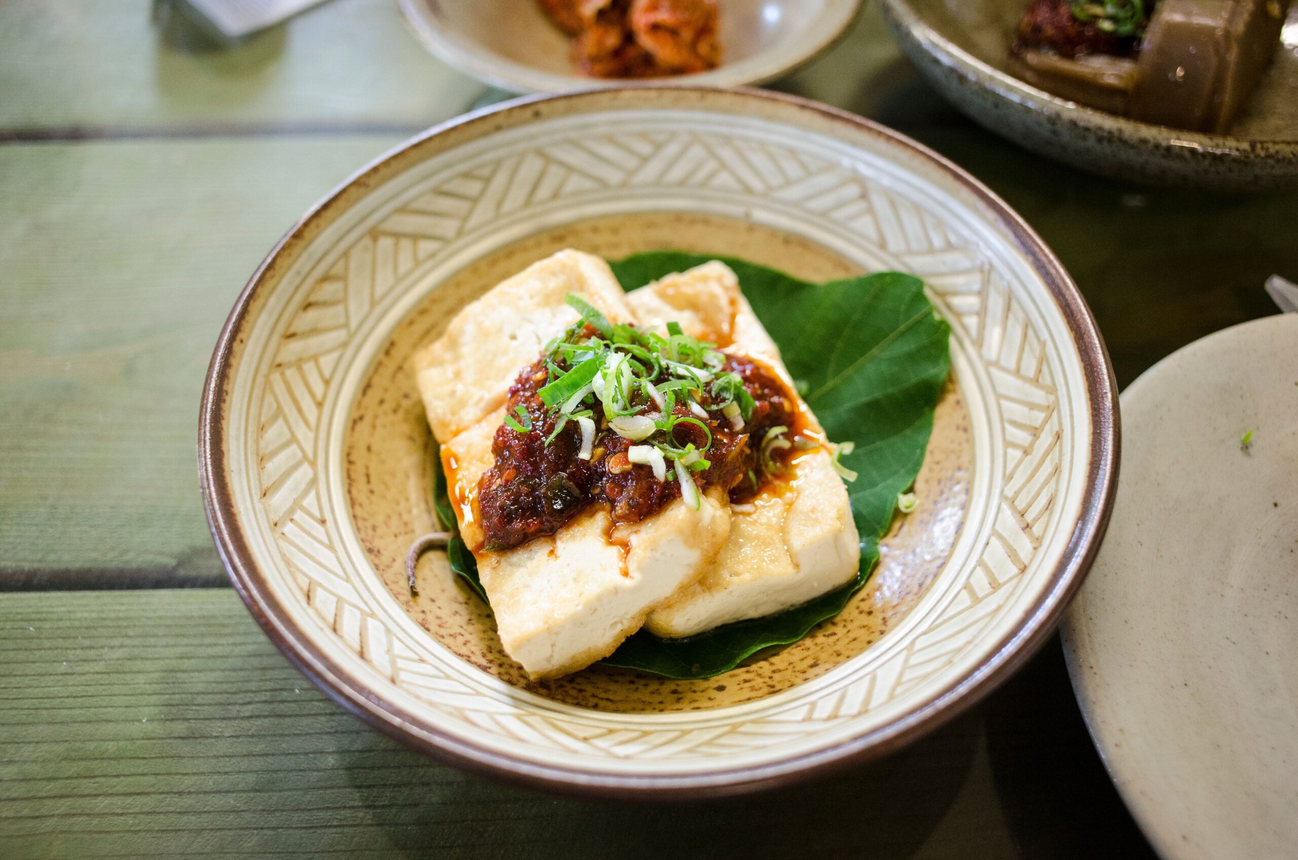 Close-up of a tofu dish topped with a spicy garnish on a decorative plate, perfect for food photography enthusiasts.
